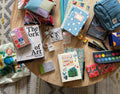 Journals, paints, and art books spread on a table for Circle Up