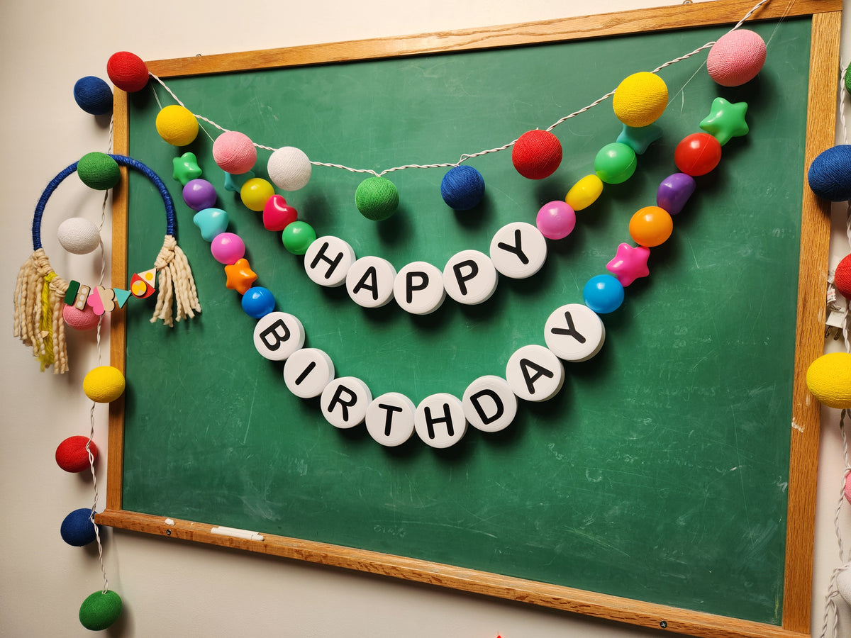 Happy Birthday pom-pom garland on a chalkboard at Nimble Craft